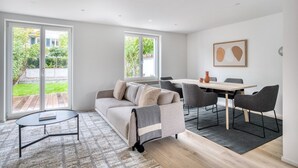 Ein modernes Wohnzimmer mit einer Couch, einem kleinen Tisch und einem Essbereich mit Stühlen.
