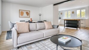 Ein modernes Wohnzimmer mit einer Couch, einem Couchtisch und einem Essbereich mit Stühlen und einem Tisch.