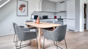 Una cocina moderna con gabinetes grises, una mesa de comedor de madera y sillas tapizadas en gris.