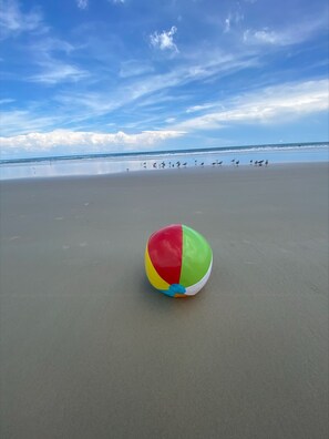 Enjoy a serene beach scene with a beach ball on the sand, overlooking the ocean.