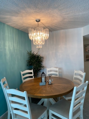Enjoy meals in this dining area with a round table and six chairs, a chandelier, and a potted plant.