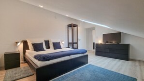Une chambre à coucher moderne avec un lit, des lampes de chevet, une commode et un téléviseur.