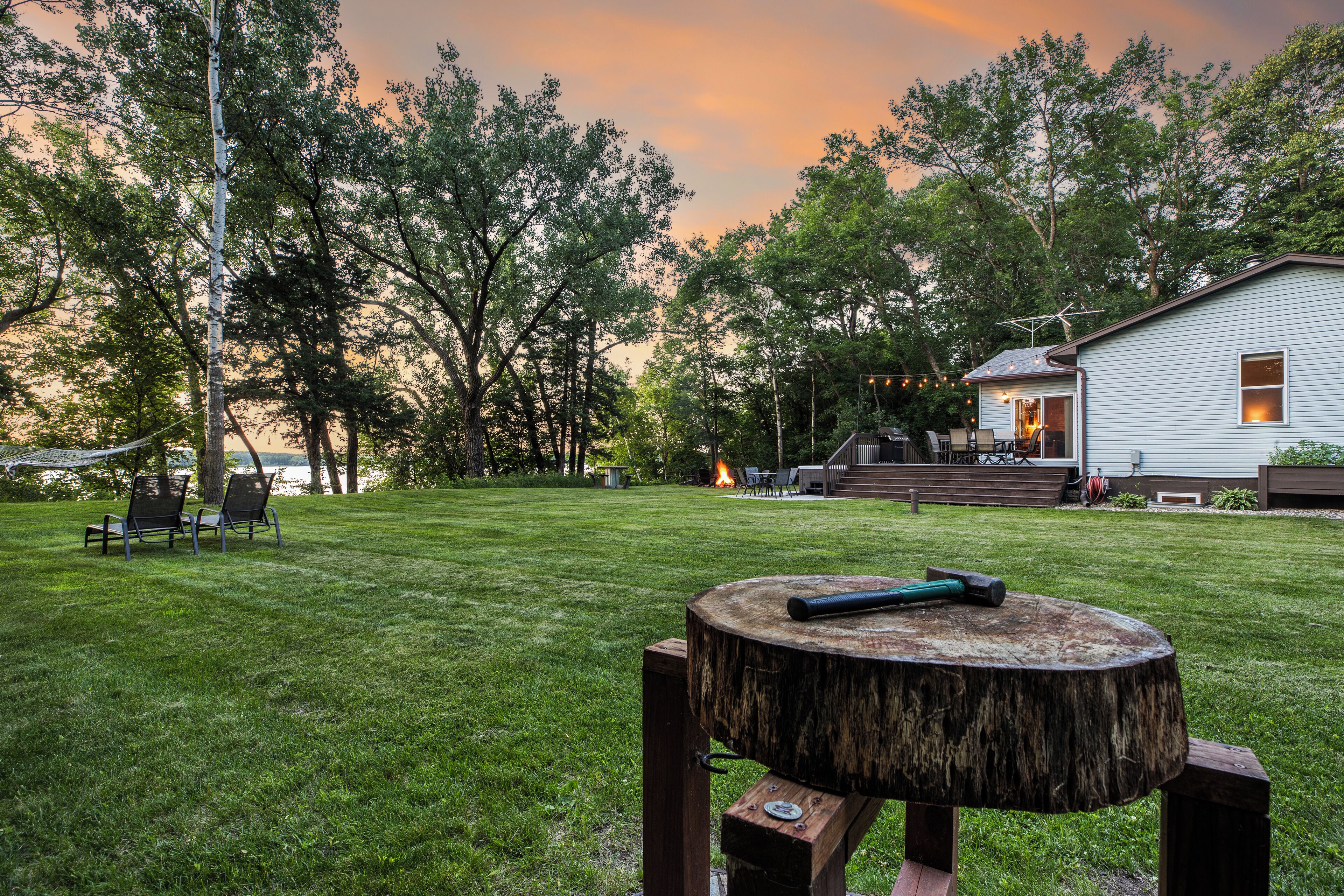 Un patio trasero con una mesa de madera, una chimenea y una casa al fondo.