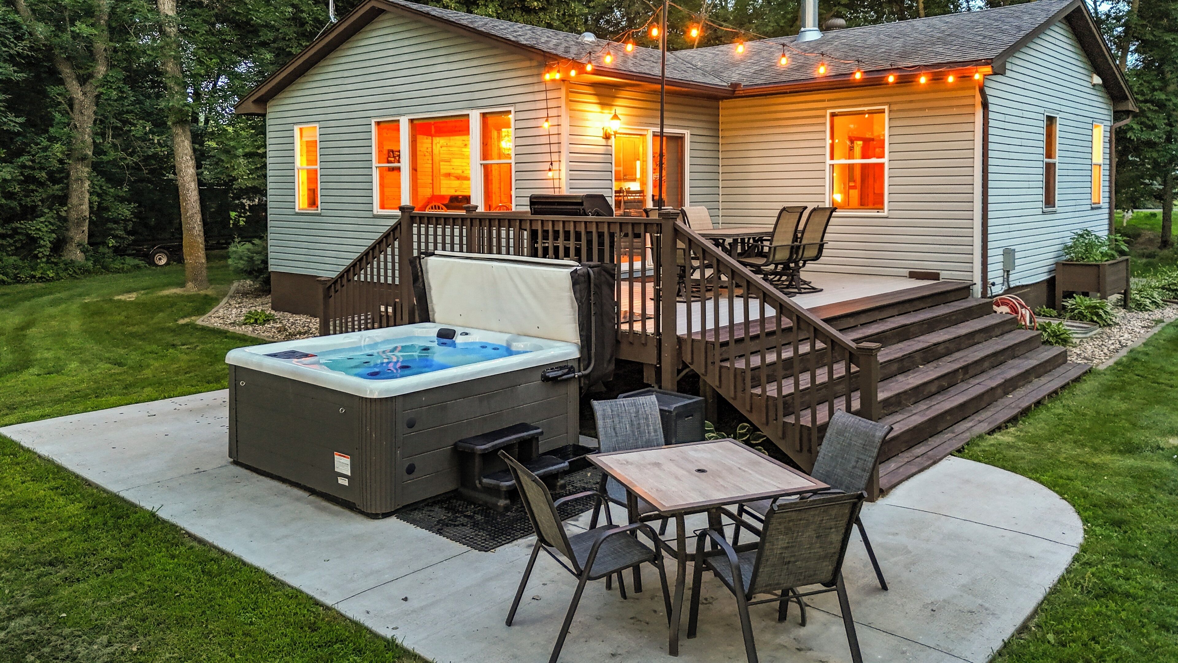 A house with a hot tub, outdoor seating, and a deck.