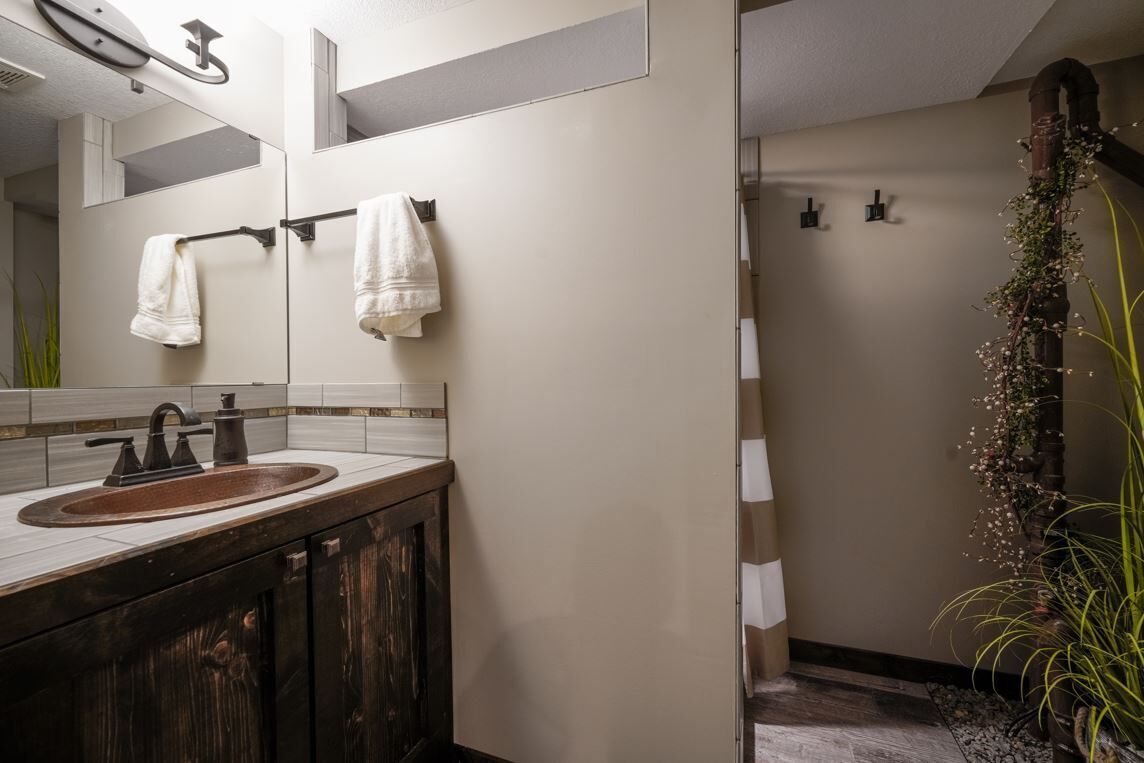 Un baño con lavamanos, espejo, toallero y zona de ducha.