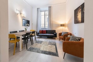 Una sala moderna con comedor, un sofá, una mesa de centro y un televisor montado en la pared.