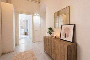 Ein Korridor mit einer Holzkonsole, einem gerahmten Bild, einer Topfpflanze und einem Spiegel an der Wand.