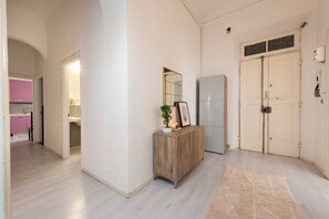 Ein Flur mit einem Holztischchen, einem Spiegel und einer Tür mit Fenster.