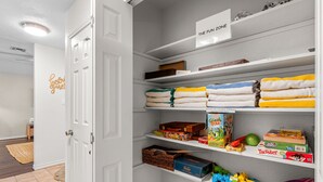 A neatly organized storage area with labeled shelves, including a 'The Fun Zone' section with toys and games.