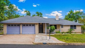 A two-story house with a garage, a chimney, and a well-maintained lawn.