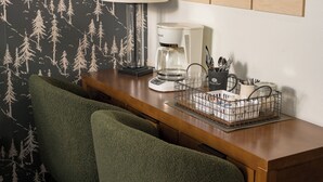 Ett hotellrum med ett skrivbord i trä, en kaffebryggare, en lampa och en stol.