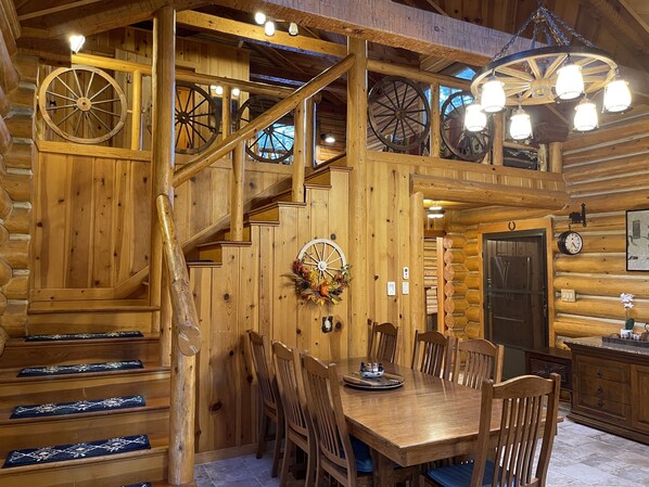 Step into this charming cabin, featuring a rustic dining area with a wooden table and chairs, a chandelier, and a cozy atmosphere.