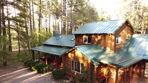 Une cabane en rondins avec un toit en métal, une véranda et un chemin de pierre menant à l’entrée.