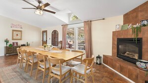 A dining area with a wooden table and chairs, a ceiling fan, and a fireplace. - Serene Home ~ Sleeps 16 ~ Kings & Queens~ 2 Kitchens~ Hot Tub ~ Starlink Wifi (Sedona)