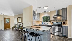 A modern kitchen with a large island, bar stools, stainless steel appliances, and a view of the outdoors. - Serene Home ~ Sleeps 16 ~ Kings & Queens~ 2 Kitchens~ Hot Tub ~ Starlink Wifi (Sedona)