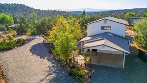 A two-story house with a garage, surrounded by a gravel driveway and a fenced yard. - Serene Home ~ Sleeps 16 ~ Kings & Queens~ 2 Kitchens~ Hot Tub ~ Starlink Wifi (Sedona)