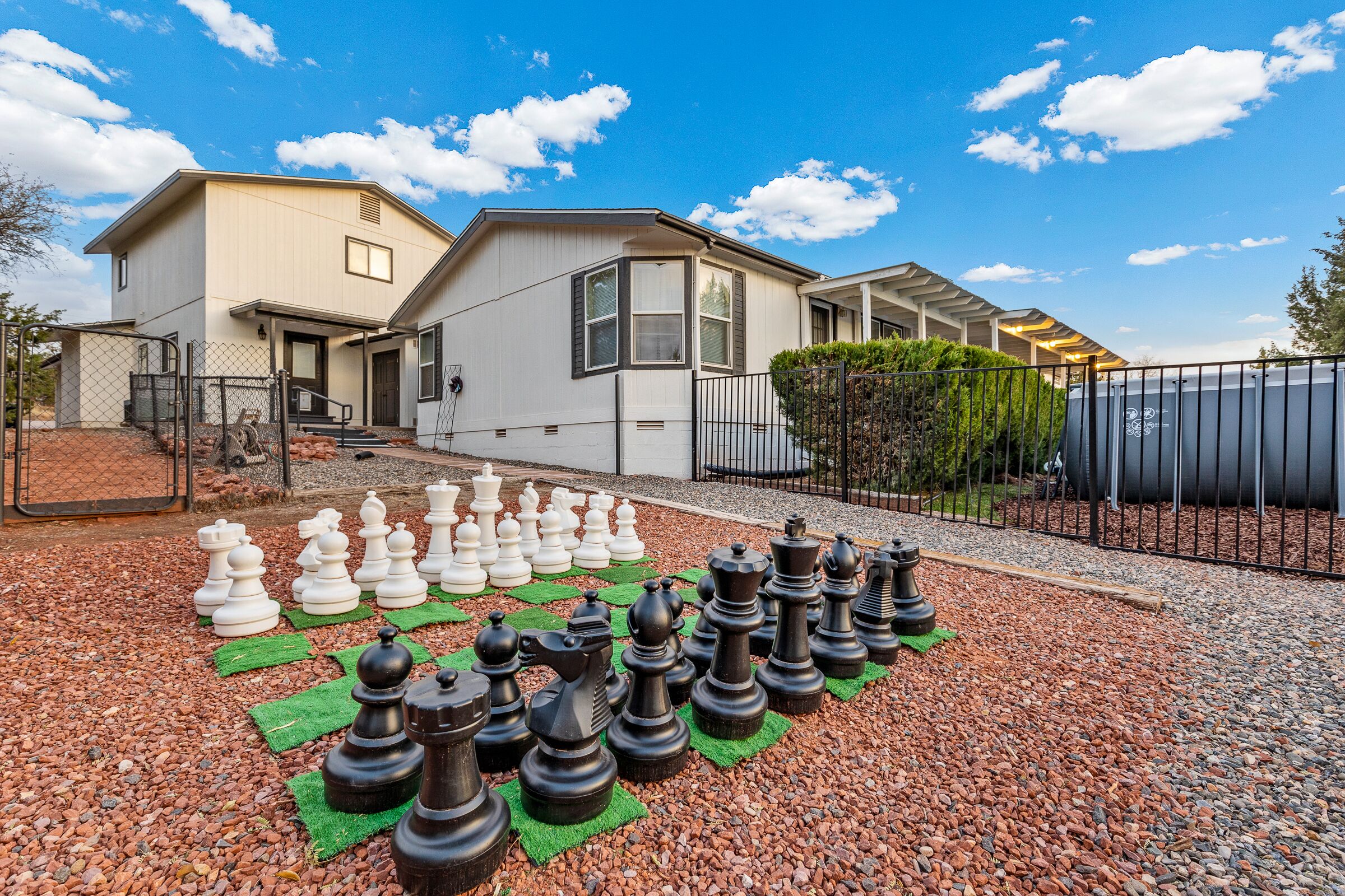 A residential area with a house and a large chessboard setup on the driveway.
