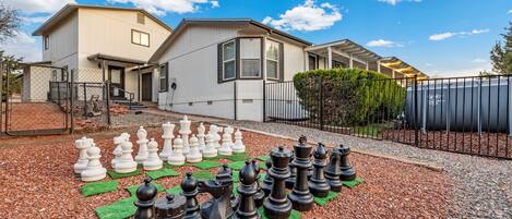 A residential area with a house and a large chessboard setup on the driveway.