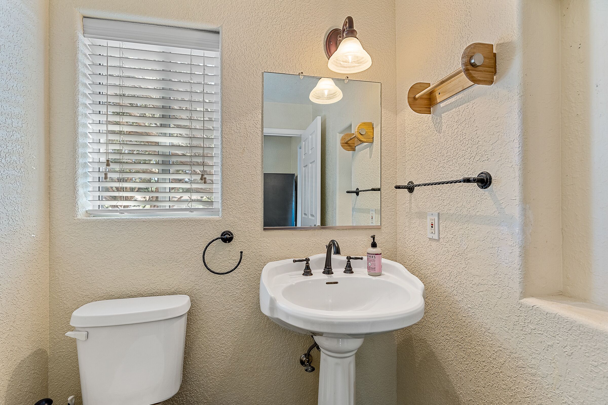 Ein Badezimmer mit Toilette, Waschbecken und einem Fenster mit Jalousien.