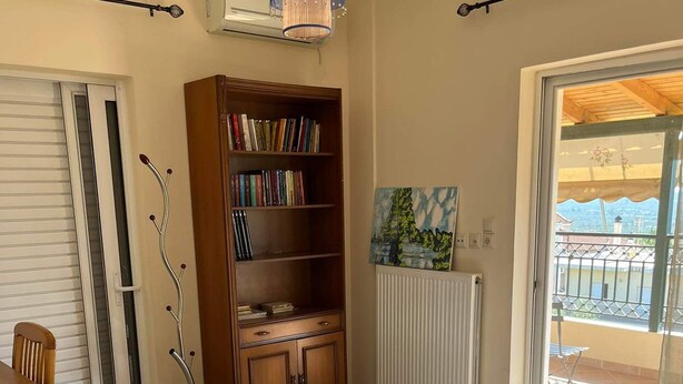 Ett sovrum med en säng, en bokhylla, ett element och utsikt över omgivningen.