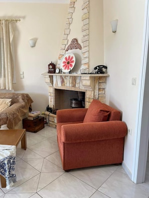 A living room with a fireplace, a sofa, a small table, and a patterned throw blanket. - Beautiful & cosy 5-Bedroom Villa - Peloponnese (Arfara, Kalamata)