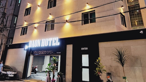 A hotel with a modern facade, multiple windows, and a sign indicating it is open for guests. - DAON HOTEL (Gimhae)