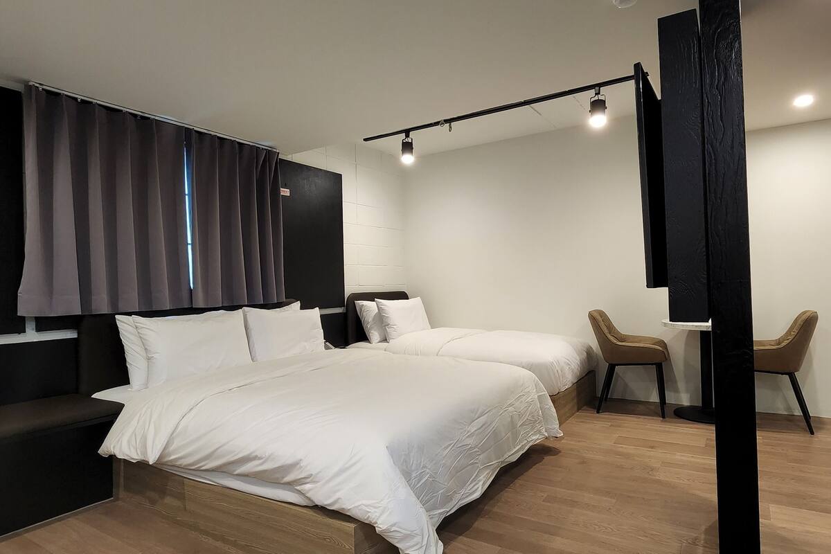 A modern hotel room with a large bed, a bench, a desk, and a chair.