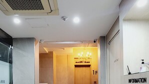 A hotel lobby with a reception desk, a chandelier, a trash bin, and an elevator. - DAON HOTEL (Gimhae)