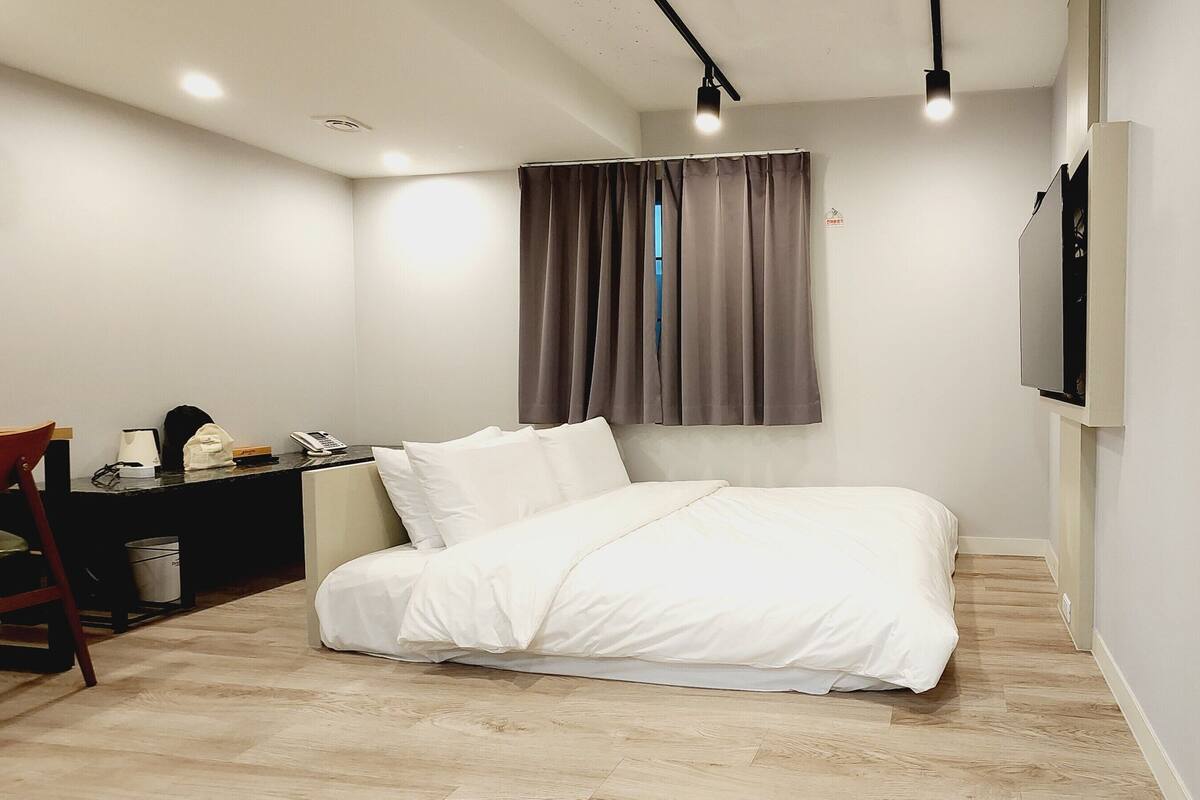 A modern bedroom with a bed, bedside table, and a desk with a chair.