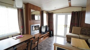 Una sala moderna con una mesa de comedor de madera, un sofá, un televisor y una chimenea.