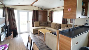 Un espacio habitable compacto con sofá, una pequeña mesa de comedor y una kitchenette.