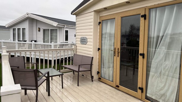 Terraza con mobiliario exterior, puerta corrediza de vidrio y vista a una casa vecina.