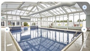 Una piscina interior con señalización clara que indica la zona poco profunda y la zona profunda.