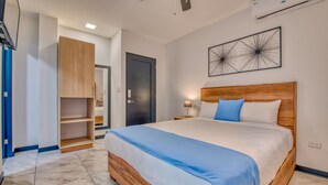 Un dormitorio con cama, mesita de noche, aire acondicionado en la pared y una puerta.