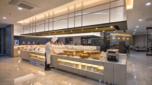 A modern buffet setup with a chef preparing food, a marble countertop, and a well-lit dining area with tables and chairs. - Grab the Ocean SONGDO (Busan)