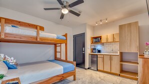 Ein kleines Zimmer mit Etagenbett, einer Küchenzeile und einem Deckenventilator.