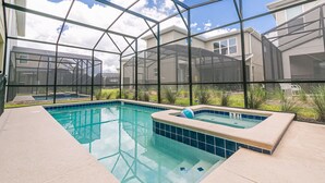 A swimming pool with a hot tub, surrounded by a glass enclosure with a view of houses. -  6 Br/5 Ba Pool/Game /Themed Handpainting Villa (Kissimmee)