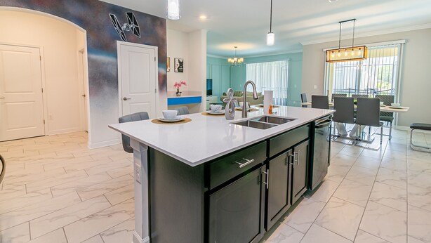 A modern kitchen with a central island, black cabinetry, and pendant lighting. -  6 Br/5 Ba Pool/Game /Themed Handpainting Villa (Kissimmee)