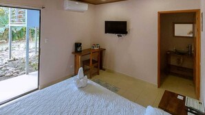 A bedroom with a large bed, a desk, a television, and a bathroom visible through an open door. - Private room for 2 people 26 km from Jaco (San Antonio de Tulín)