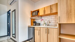 Een moderne keuken met houten kastjes, een ingebouwde magnetron en een koffieapparaat.