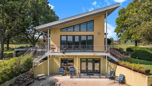 A two-story building with a balcony, outdoor seating, and a view of the surrounding landscape.