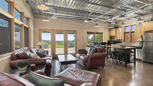 A spacious living area with leather sofas, a coffee table, and a kitchen with stainless steel appliances.