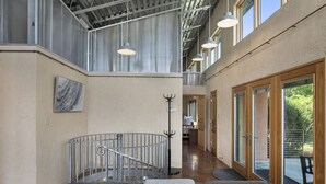 A spacious interior with a high ceiling, a staircase, and a seating area with a view to the outdoors.