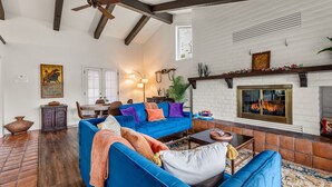 A living room with a blue sofa, a fireplace, and a ceiling fan. - Large Spanish Villa ~ Sleeps 14~ Gym ~ GameRm~ Pool ~ Views  (Sedona)