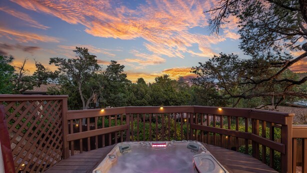 A hot tub on a wooden deck with a view of trees and a sunset. - Large Spanish Villa ~ Sleeps 14~ Gym ~ GameRm~ Pool ~ Views  (Sedona)