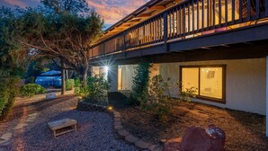 A building with a wooden balcony overlooking a garden area with a gravel path and a wooden bench. - Large Spanish Villa ~ Sleeps 14~ Gym ~ GameRm~ Pool ~ Views  (Sedona)