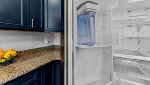 A kitchen with dark blue cabinets, a granite countertop, and a water dispenser.