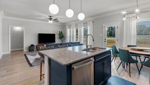 A modern kitchen with a central island, built-in appliances, and a dining area with a table and chairs.