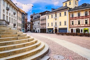 A cobblestone square with historic buildings, a stone staircase, and outdoor seating.