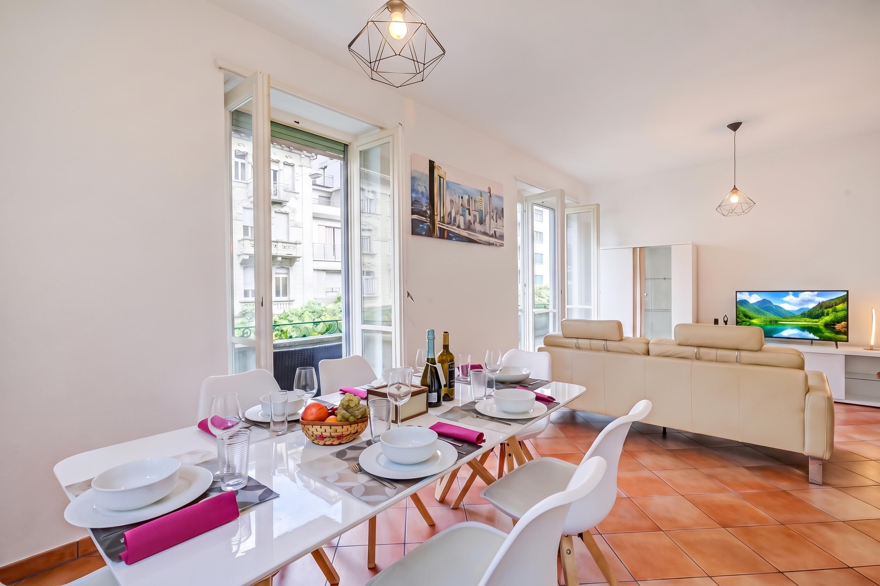 A dining area with a table set for four, a sofa, and a television in the background.